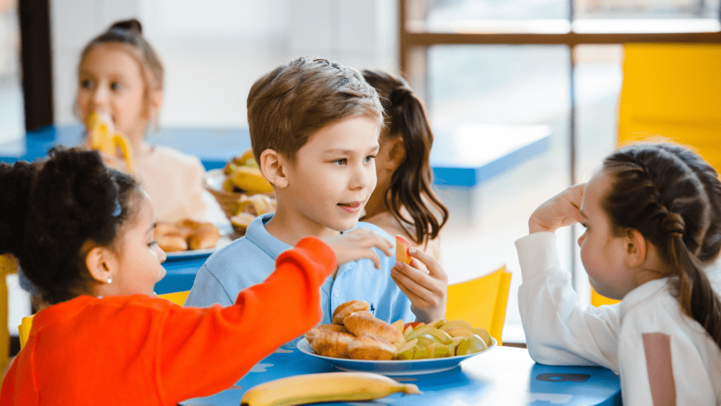 a group of children eating food in a cafeteria