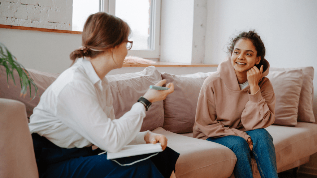 two people sitting on a couch talking to each other