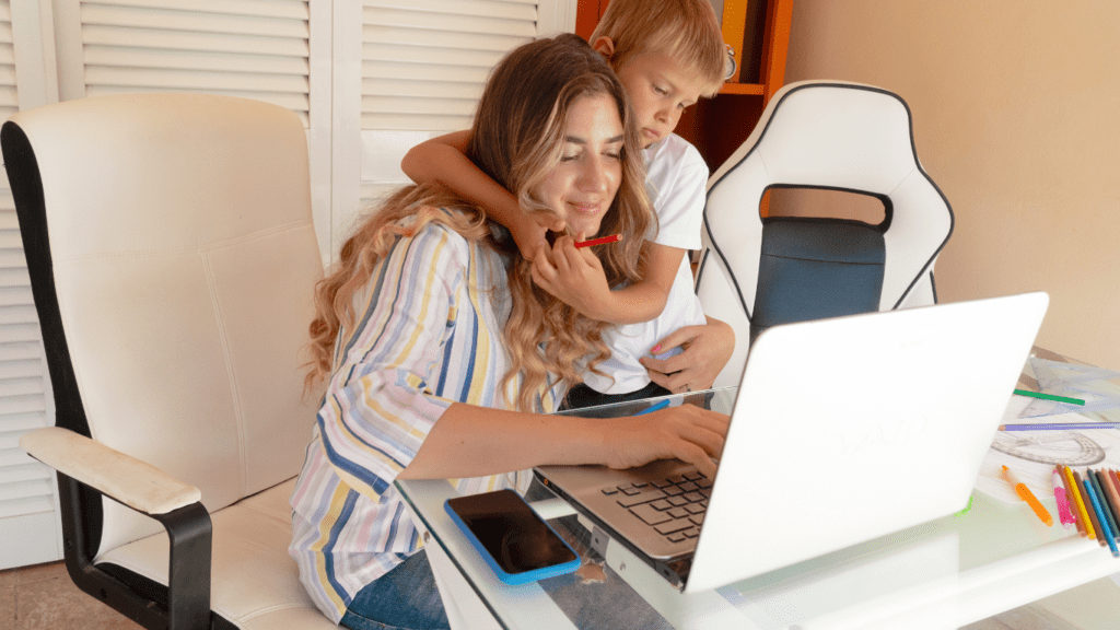 Someone holding a baby while sitting in front of a laptop