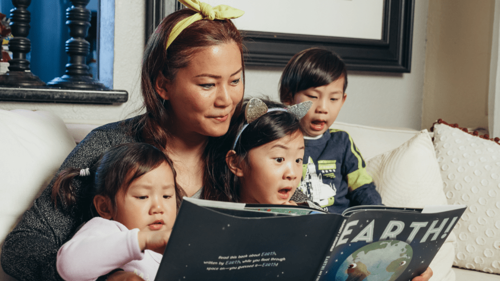 a person reads to their children while sitting on a couch