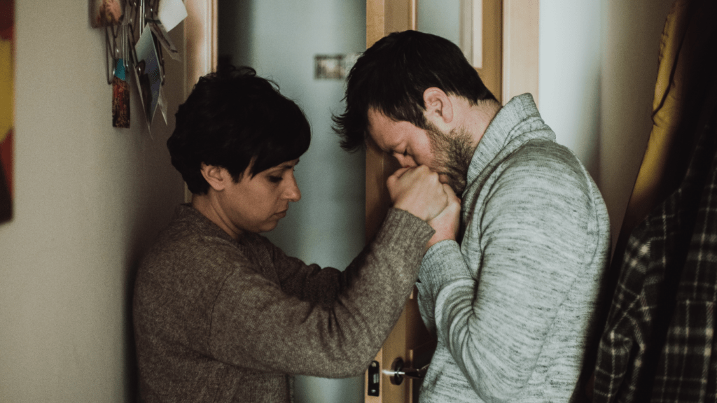 Two people sitting on a bed holding hands