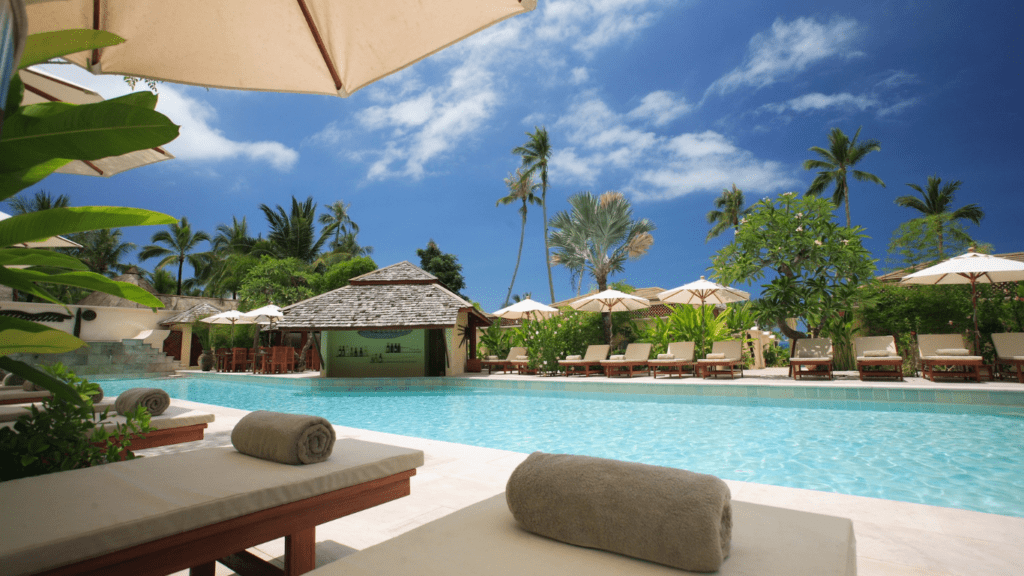 an outdoor swimming pool with lounge chairs and umbrellas