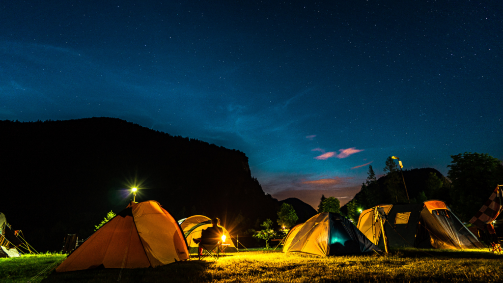 a group of tents at night in a field with a mountain in the background