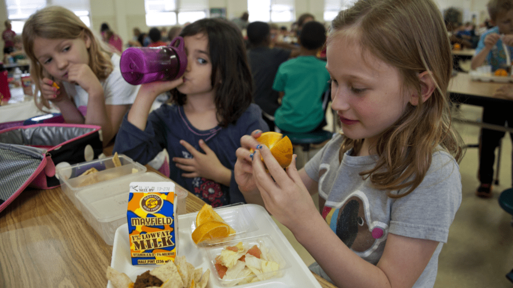 a group of children eating food in a cafeteria