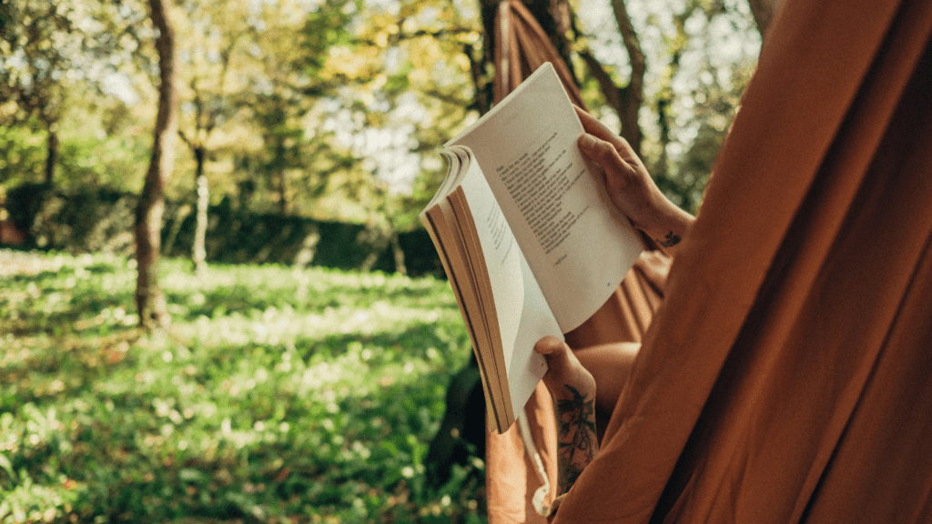 a person reading a book in a hammock in the forest