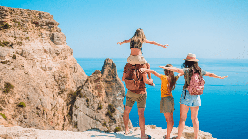 three people standing on the edge of a cliff with their arms outstretched