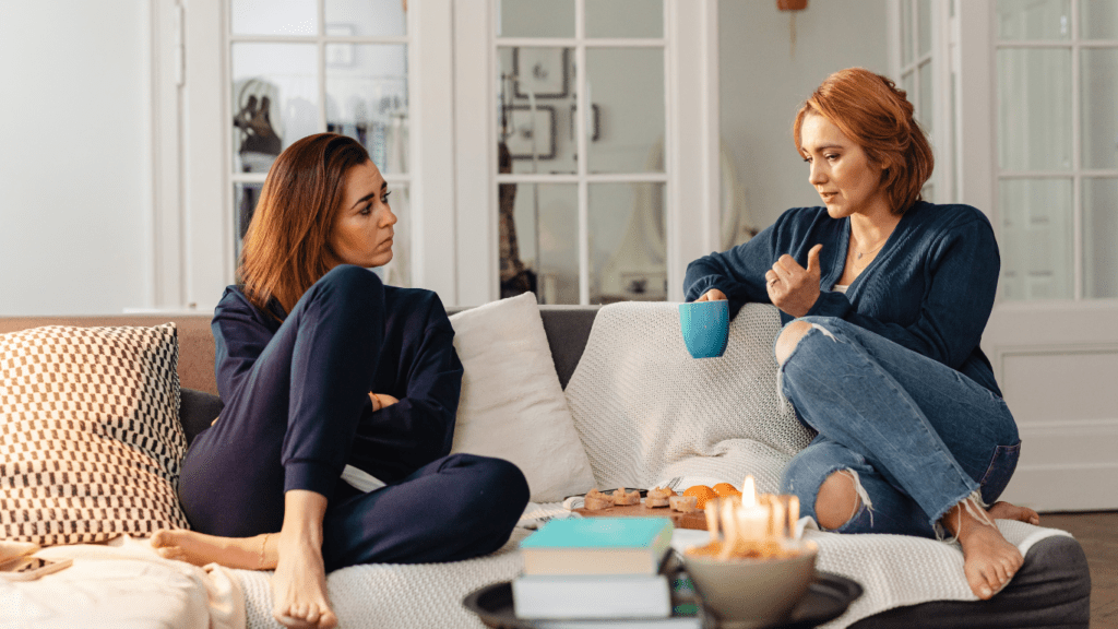 two people sitting on a couch talking to each other